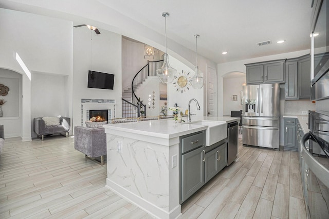 kitchen featuring visible vents, wood finish floors, gray cabinets, appliances with stainless steel finishes, and a sink