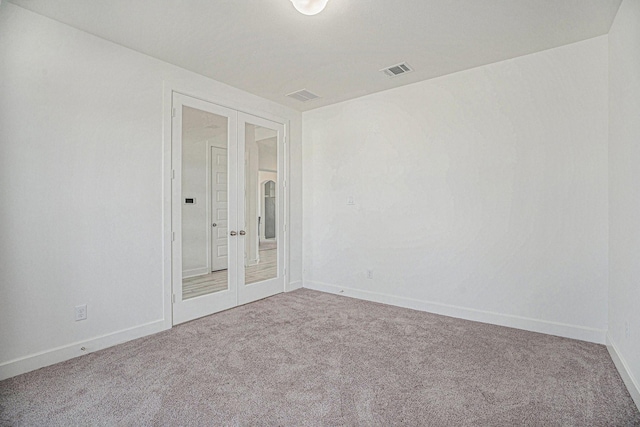 carpeted spare room with visible vents, french doors, and baseboards