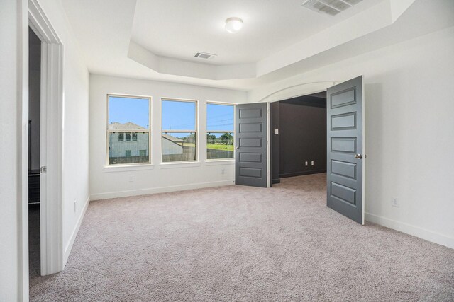 unfurnished bedroom with a raised ceiling, carpet flooring, visible vents, and baseboards