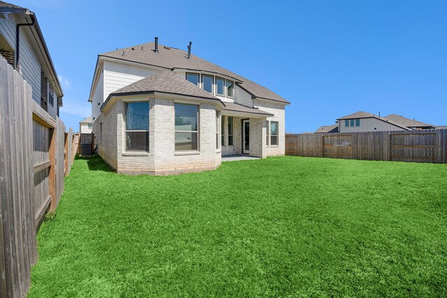 back of house featuring central AC unit, a yard, a fenced backyard, a shingled roof, and brick siding