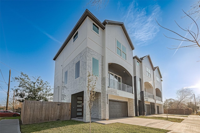 view of front of property with stucco siding, concrete driveway, an attached garage, and fence