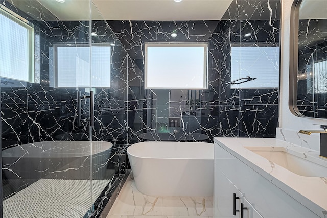 bathroom featuring a freestanding tub, tile walls, marble finish floor, and vanity