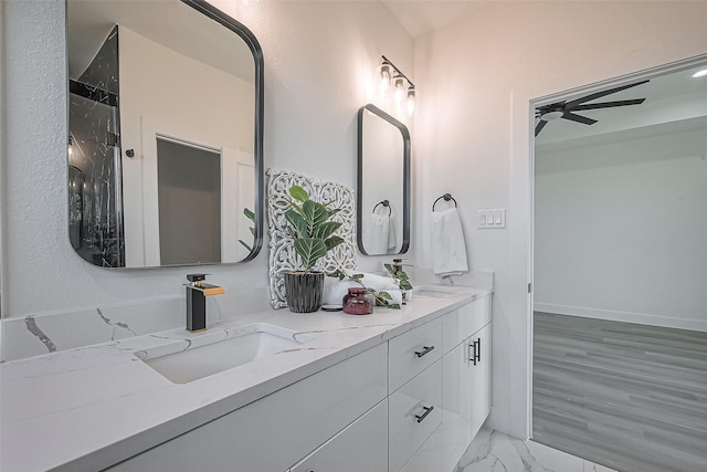 bathroom with double vanity, marble finish floor, ceiling fan, and a sink