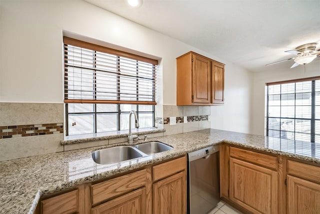 kitchen with a ceiling fan, a sink, tasteful backsplash, stainless steel dishwasher, and light stone countertops