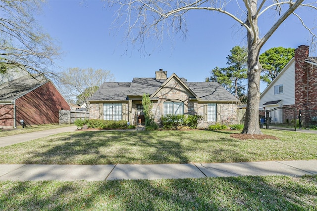 view of front of house with a front yard, fence, stone siding, and a chimney