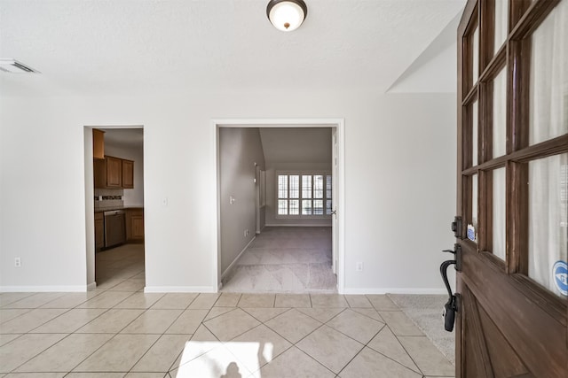 entrance foyer with visible vents, a textured ceiling, light tile patterned floors, baseboards, and light colored carpet