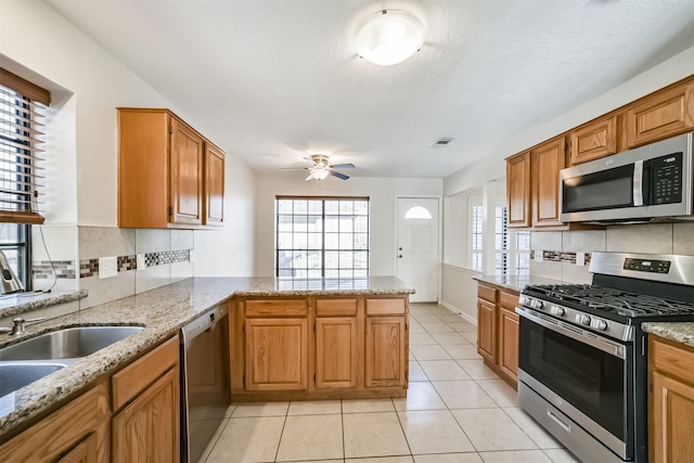 kitchen featuring light tile patterned floors, visible vents, a peninsula, stainless steel appliances, and decorative backsplash