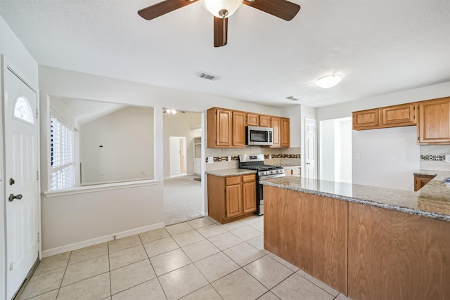 kitchen with light tile patterned floors, light stone countertops, visible vents, appliances with stainless steel finishes, and backsplash