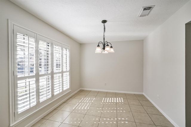 unfurnished room with light tile patterned floors, visible vents, a textured ceiling, and a chandelier