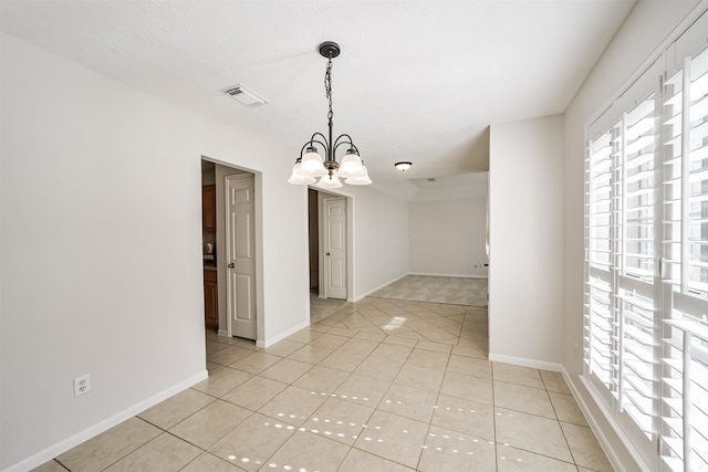 empty room featuring light tile patterned floors, visible vents, baseboards, and a notable chandelier