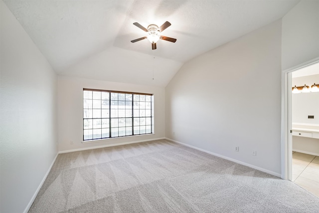 spare room with baseboards, light carpet, and lofted ceiling