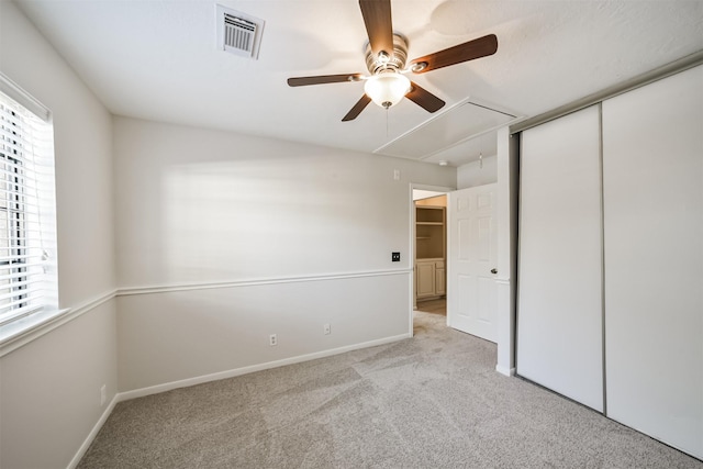 unfurnished bedroom with carpet, visible vents, baseboards, attic access, and a closet