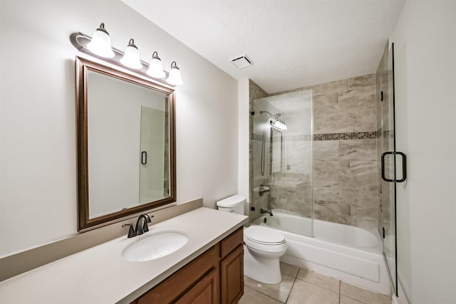 bathroom featuring tile patterned flooring, visible vents, toilet, combined bath / shower with glass door, and vanity