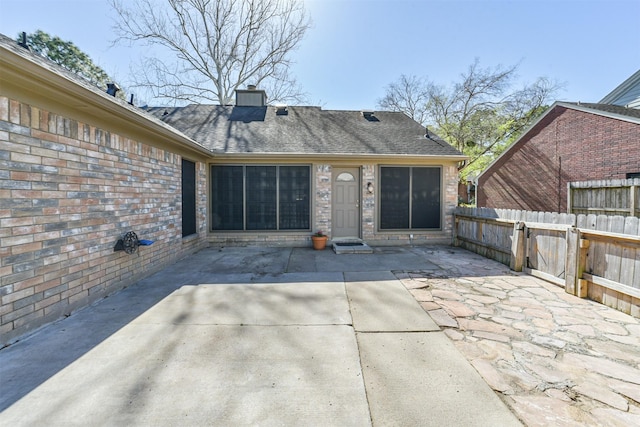 back of house with a patio area, fence, brick siding, and roof with shingles