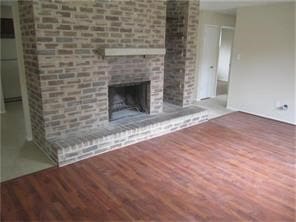 unfurnished living room featuring a brick fireplace and wood finished floors