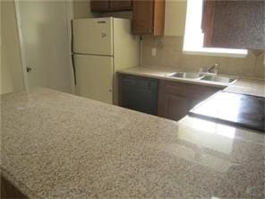 kitchen with speckled floor, freestanding refrigerator, a sink, dishwasher, and brown cabinets