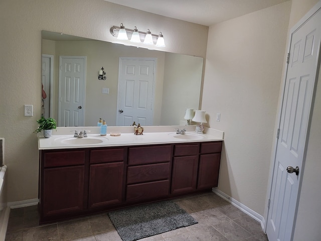 bathroom with double vanity, baseboards, and a sink