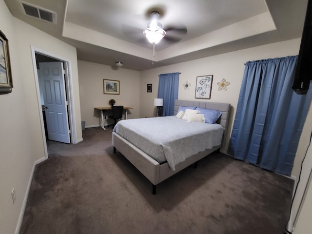 carpeted bedroom featuring a tray ceiling, baseboards, visible vents, and ceiling fan