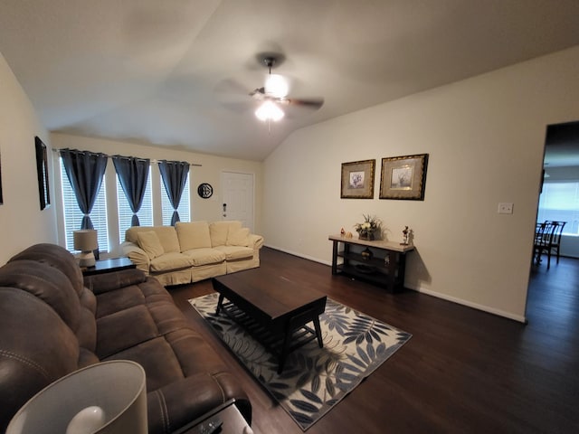 living room featuring baseboards, dark wood-type flooring, a ceiling fan, and vaulted ceiling