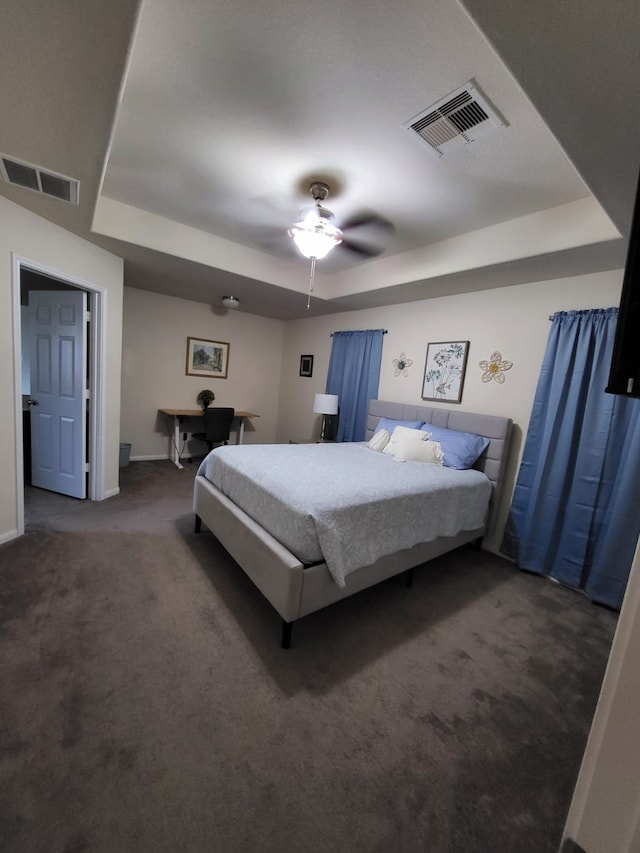 bedroom with a raised ceiling, carpet flooring, baseboards, and visible vents