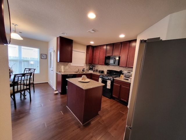 kitchen featuring visible vents, a kitchen island, black appliances, and dark wood-style floors