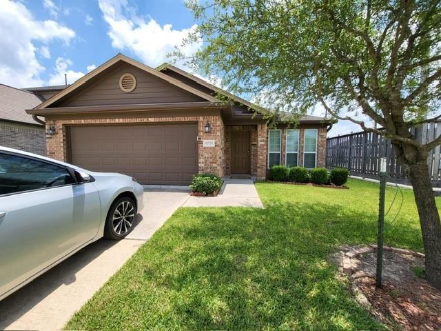 ranch-style house featuring a garage, driveway, brick siding, and a front yard