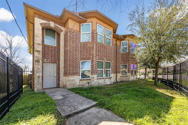 view of front of home with stone siding, brick siding, fence private yard, and a front lawn