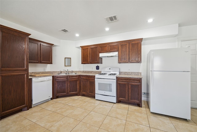 kitchen featuring under cabinet range hood, visible vents, white appliances, and a sink