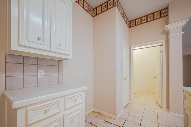 kitchen with ornate columns, light countertops, white cabinets, and backsplash