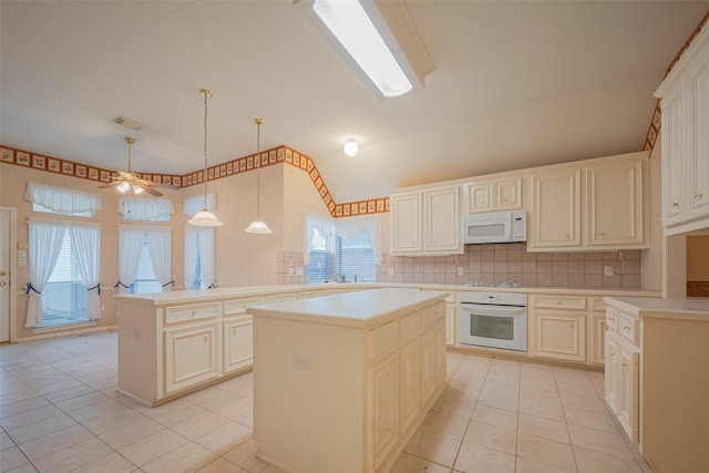 kitchen featuring a wealth of natural light, white appliances, a kitchen island, and light tile patterned floors