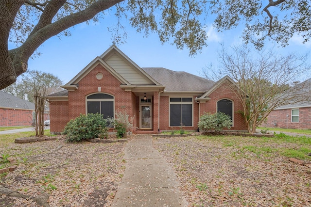 view of front of home featuring brick siding and roof with shingles