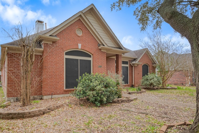 view of front of property with brick siding, a chimney, and a shingled roof