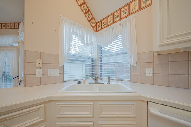 kitchen featuring a sink, tasteful backsplash, white dishwasher, and light countertops