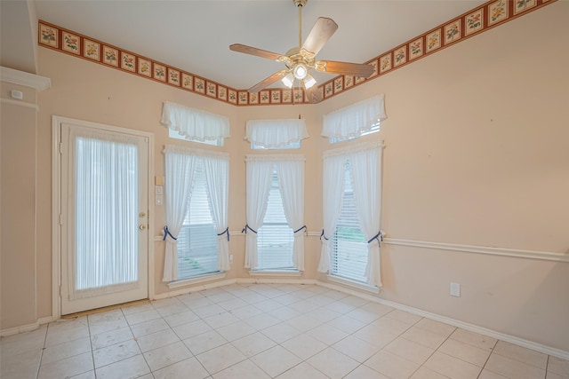 tiled empty room featuring baseboards and ceiling fan