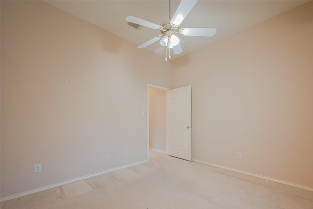 spare room featuring light colored carpet, baseboards, and ceiling fan