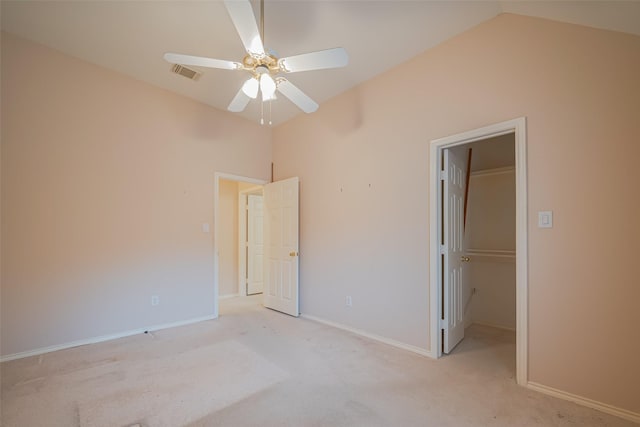 unfurnished bedroom with a spacious closet, visible vents, light colored carpet, and vaulted ceiling