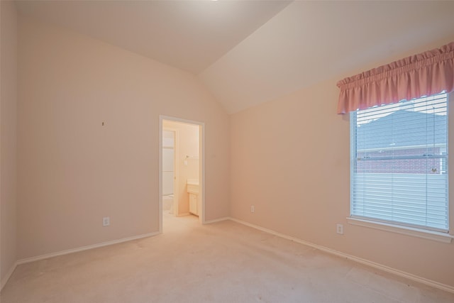 spare room with light colored carpet, baseboards, and vaulted ceiling