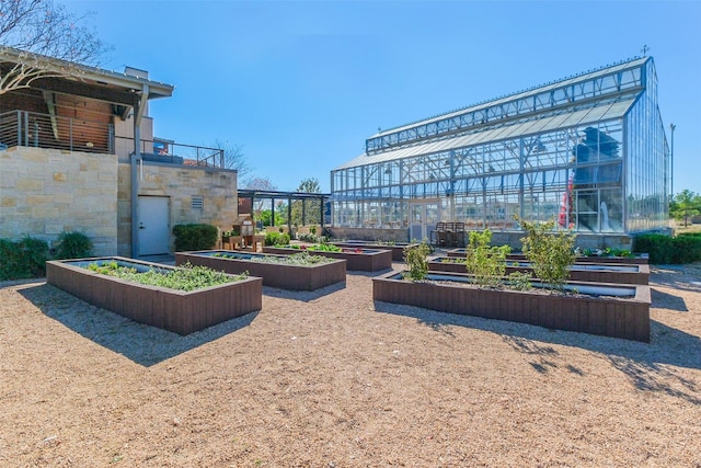 view of property's community with a garden, a greenhouse, and an outdoor structure