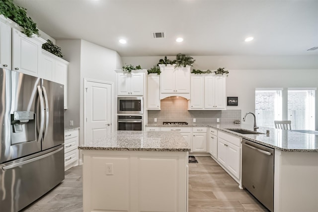 kitchen featuring decorative backsplash, a peninsula, stainless steel appliances, white cabinetry, and a sink