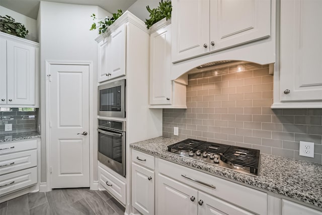 kitchen featuring light stone counters, stainless steel appliances, and white cabinets