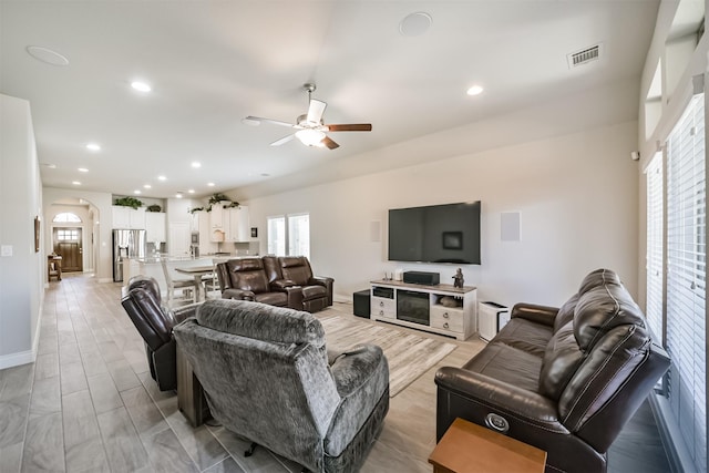 living area featuring a ceiling fan, visible vents, baseboards, recessed lighting, and arched walkways