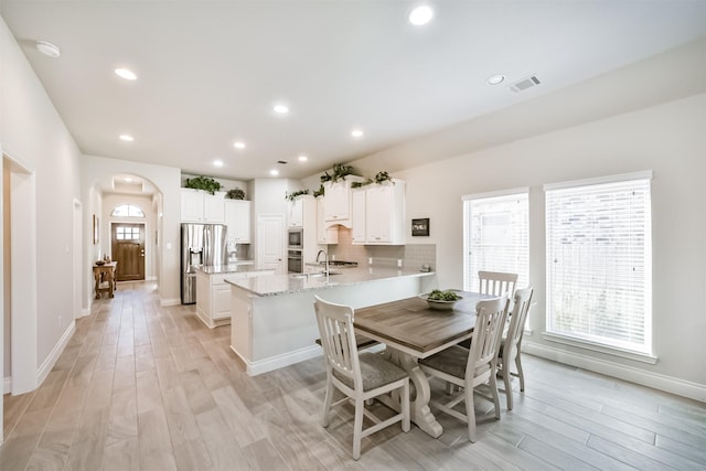 dining area featuring recessed lighting, visible vents, arched walkways, and light wood-style flooring