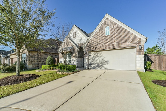 view of front of home featuring a front yard, fence, concrete driveway, stone siding, and brick siding