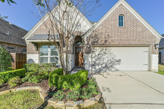 view of front of property featuring brick siding, driveway, a garage, and fence