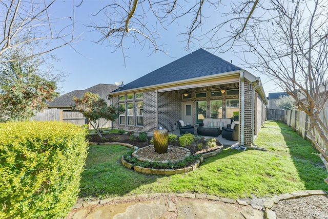 rear view of house with brick siding, an outdoor living space, roof with shingles, a fenced backyard, and a yard