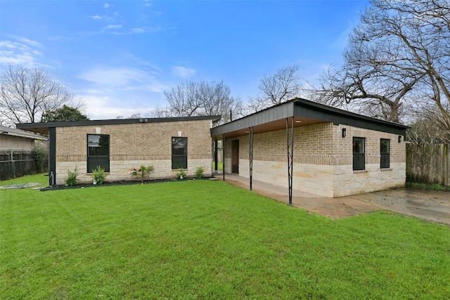 back of property featuring brick siding, a lawn, fence, and stone siding