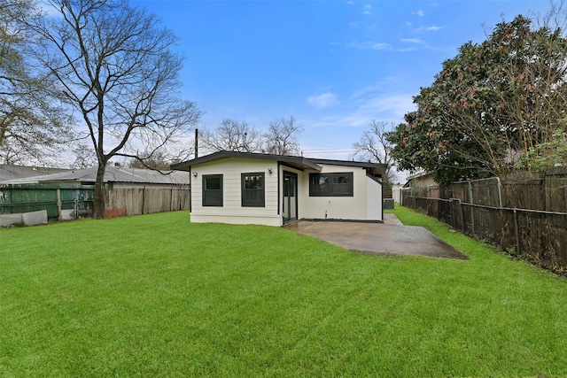 rear view of property featuring a yard, a patio, and a fenced backyard