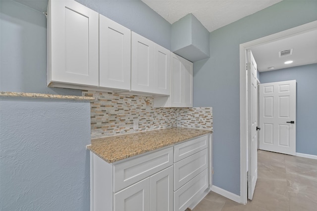 kitchen featuring visible vents, white cabinets, baseboards, and decorative backsplash