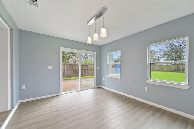 unfurnished room with visible vents, baseboards, and wood finished floors