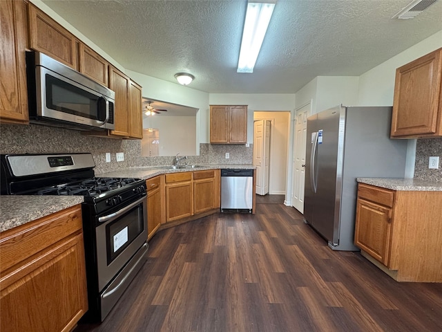 kitchen with visible vents, dark wood finished floors, a sink, appliances with stainless steel finishes, and brown cabinets